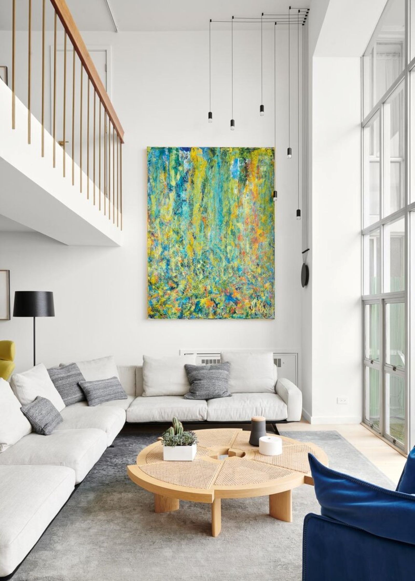 A large abstract painting with vibrant colors hangs above a sectional sofa in a modern living room.