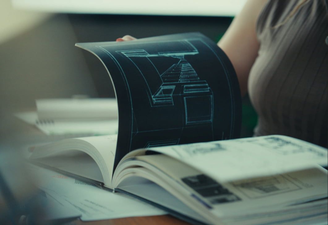 Kailey flips through a book showing building model imagery.