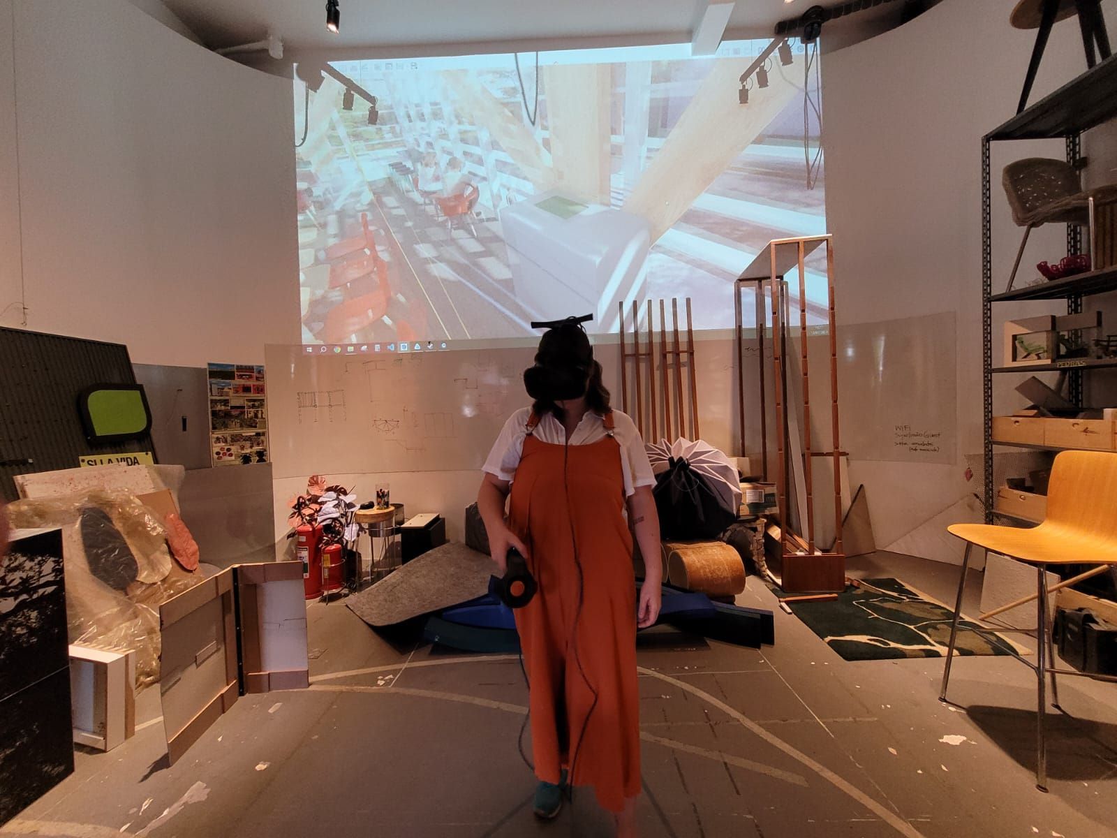 Photograph of a person using VR glasses, with their view screen behind them. Image courtesy of Superlimão.
