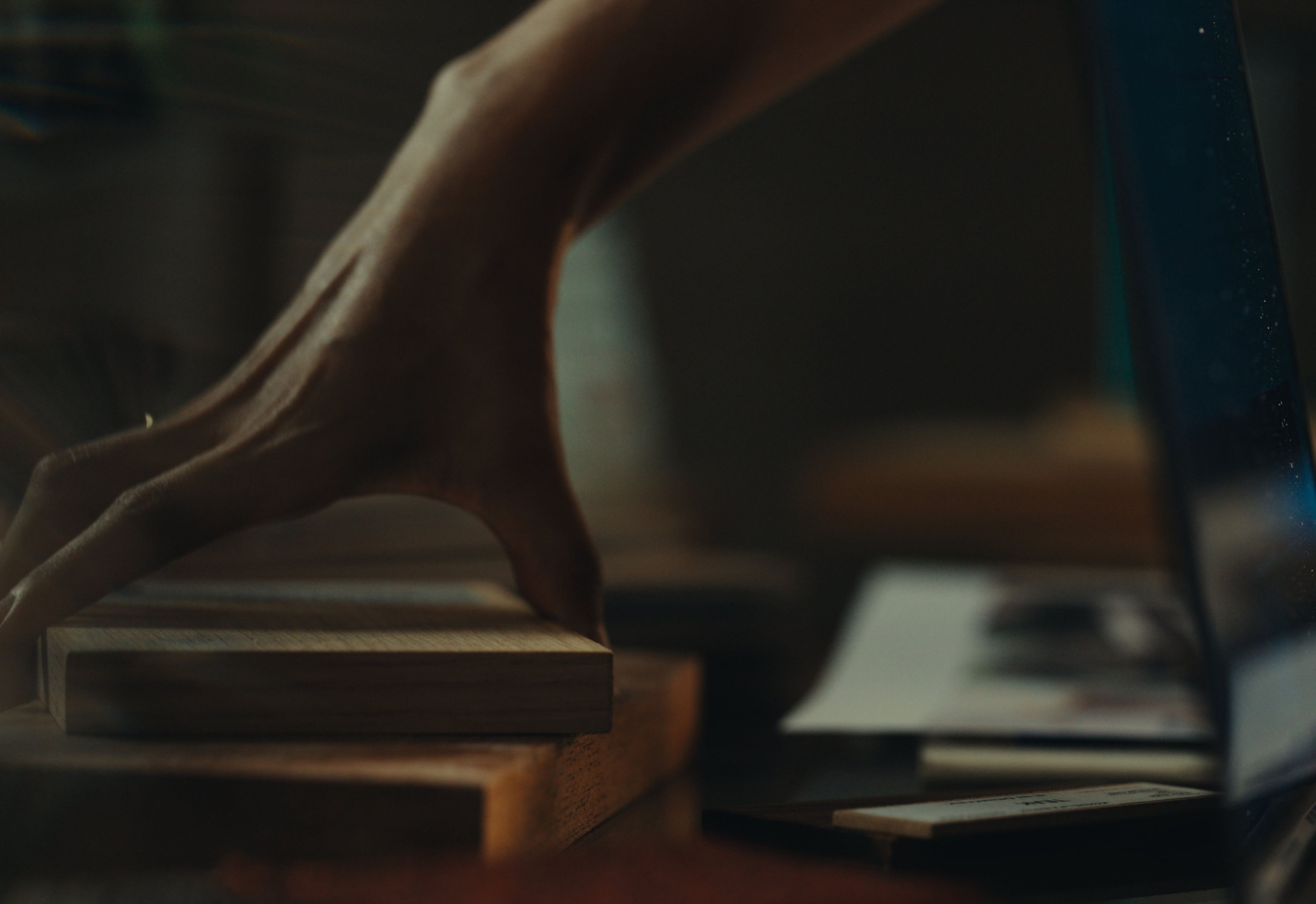 Taryn holds a block of wood in her workspace.